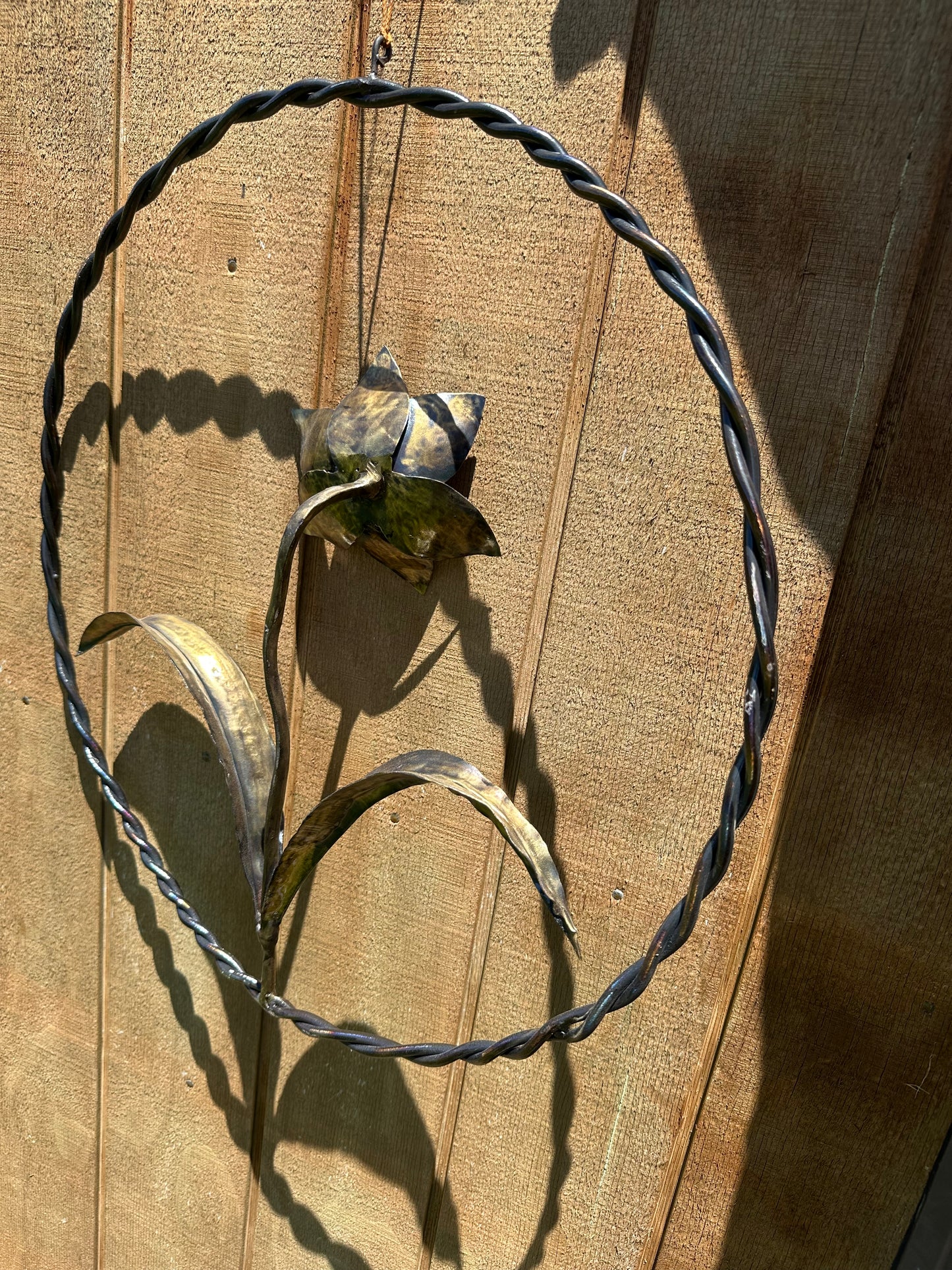 Metal daffodil sculpture with bronze coloring, set inside a steel wall ring.