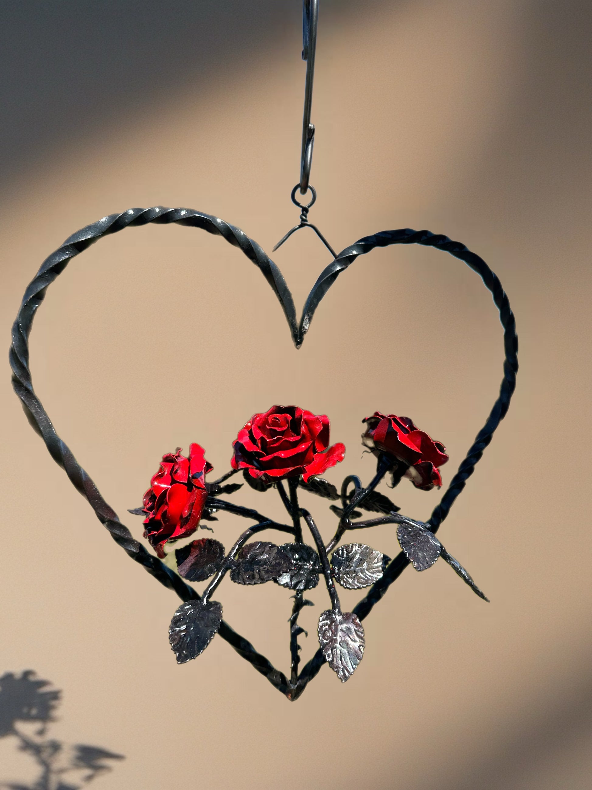 Rose Heart Garland hangs with red steel roses in a heart shaped from steel 