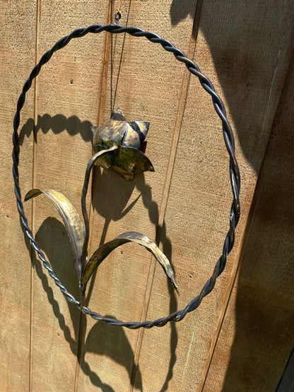 Metal daffodil sculpture with bronze coloring, set inside a steel wall ring.