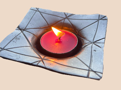 This is a steel tealight candle holder which has had detail chiseled into the steel. it shows a candle aflame within the steel which has been pressed by hand into shape. 